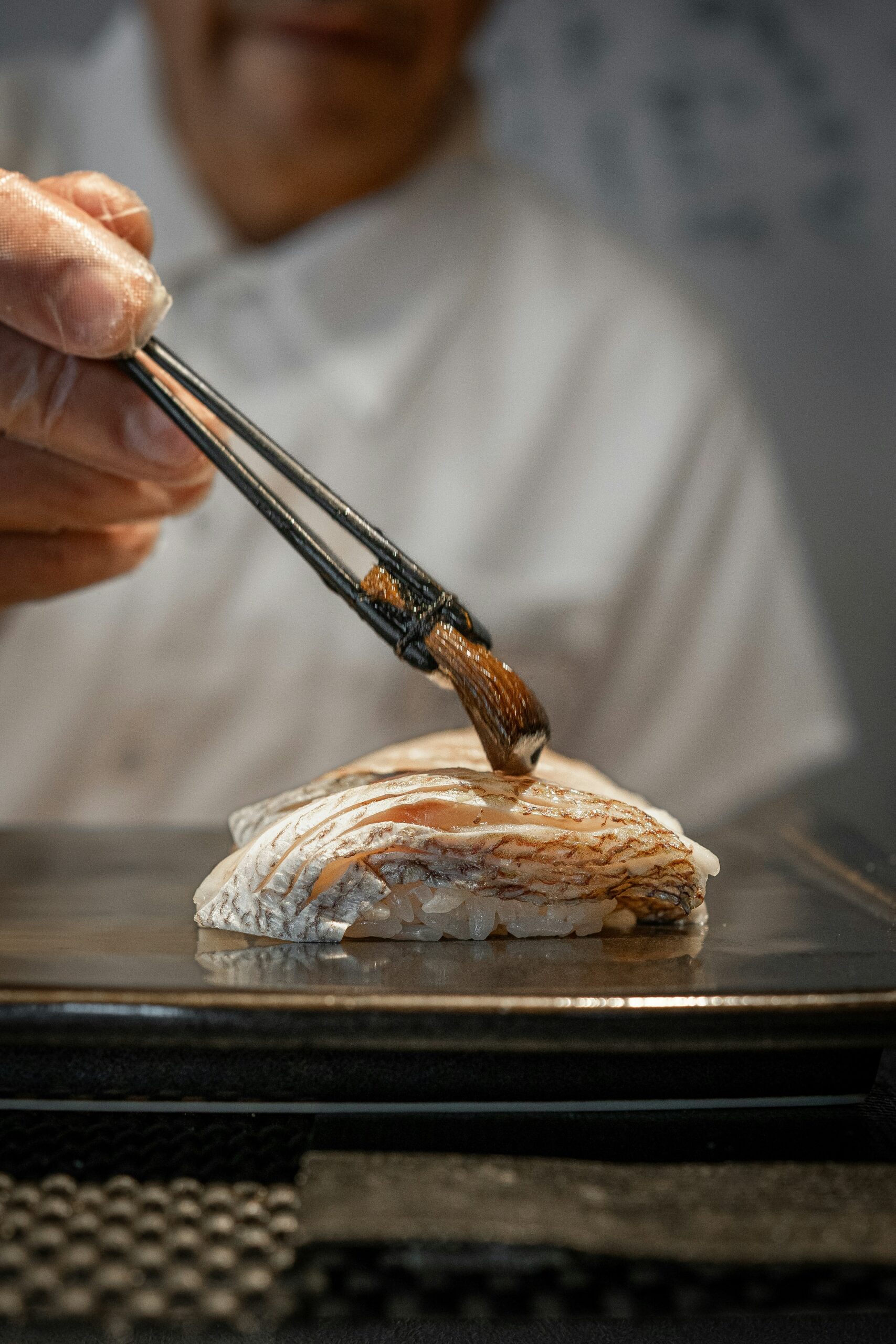 The Art of Sushi-Making: A Step-by-Step Guide to Creating Delicious and Authentic Japanese Rolls a person holding chopsticks over a piece of food